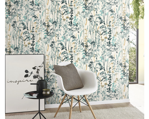 Ein Raum mit einer floralen Tapete in blaugrünen und beigen Tönen, einem weißen Stuhl mit Kissen, einem Beistelltisch mit Dekoration und einem Bild.