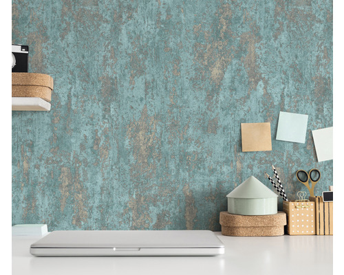 Szene mit einer strukturierten Tapete, einem Laptop und Büroartikeln auf einem weißen Schreibtisch.