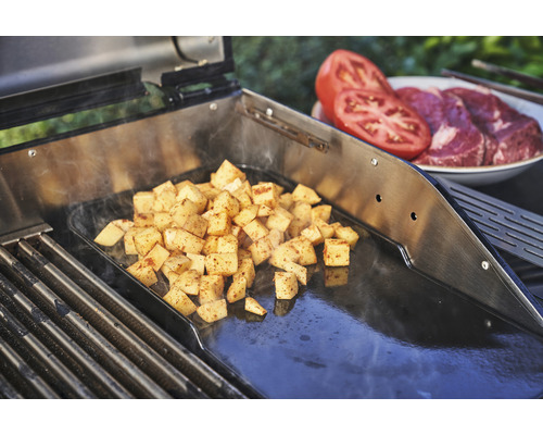 Zubereitete Kartoffelwürfel auf einer Grillplatte neben Tomaten und Fleisch