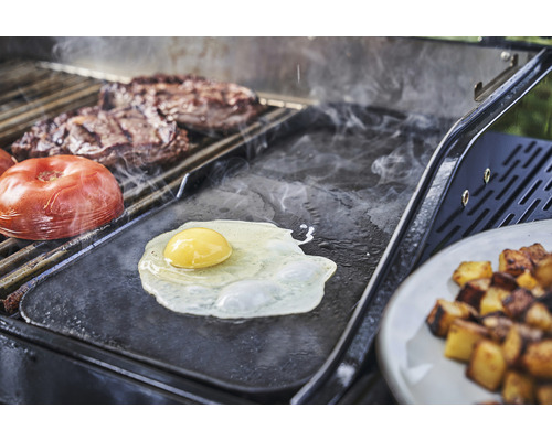 Blick auf einen Grill mit Spiegelei, Tomate, Steak und Bratkartoffeln.