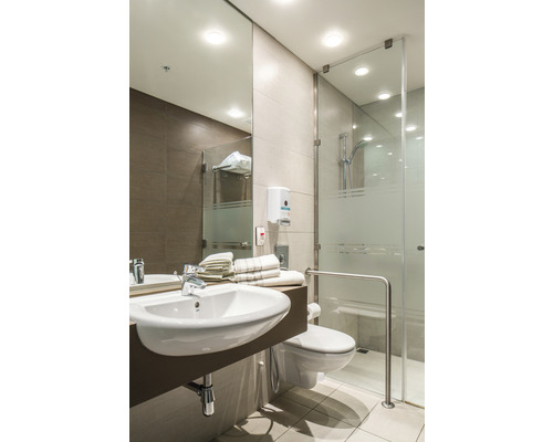 Badezimmer mit Waschbecken, Toilette und Dusche mit Glastüren