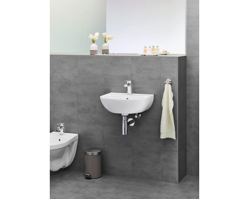 Badezimmer mit Waschtisch, Bidet, Mülleimer und Handtuchhalter an grauer Wand