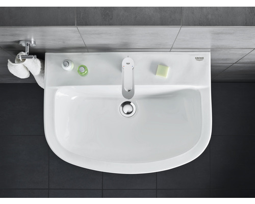 Aufsicht auf ein Waschbecken mit Armatur, Seife, Handtuch und Pflegeprodukten im Badezimmer