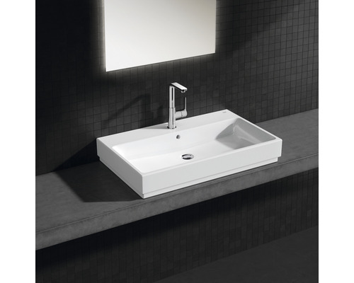 Rechteckiger Waschtisch aus Keramik mit Armatur auf einer Ablage im Badezimmer.