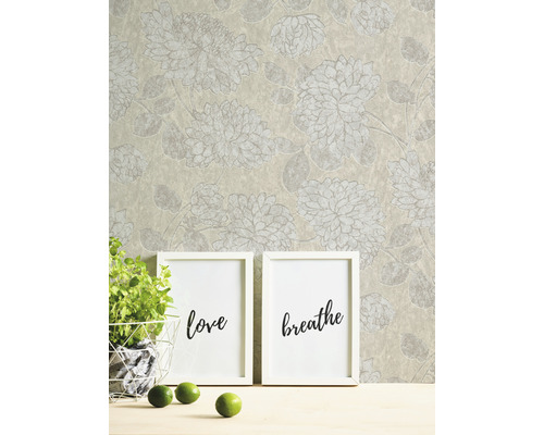 Tapete mit Blumenmuster, zwei Bilderrahmen mit den Aufschriften Liebe und Atmen, Topfpflanze und Limetten auf einem Tisch