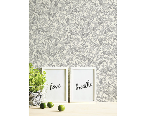 Dekorative Tapete mit Pflanzenmuster im Hintergrund, kombiniert mit zwei Bildern und einer Pflanze.