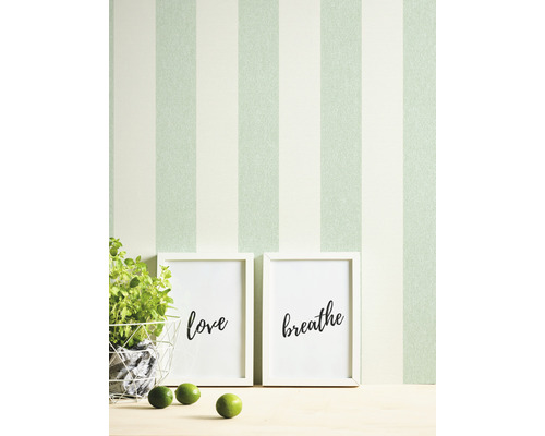 Zimmer mit gestreifter Tapete, Pflanzen, Limetten und Bildern mit den Aufschriften Liebe und Atmen