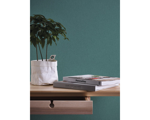 Dekorative Zimmerpflanze in Papierhülle mit zwei Büchern auf einem Holztisch mit Schublade