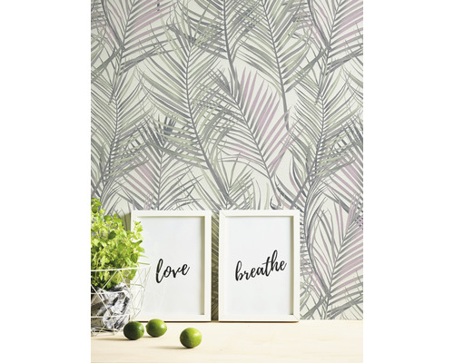 Szene mit Palmblattmuster-Tapete, zwei Bilderrahmen mit den Aufschriften Liebe und Atmen, Topfpflanze und Limetten