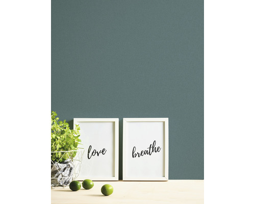 Wandgestaltung mit grüner Farbe, zwei Bildern mit den Aufschriften Liebe und Atmen, einer Pflanze und Limetten