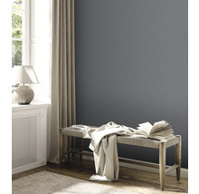Wohnzimmer mit grauer Wand, Bank, Buch und Tagesdecke