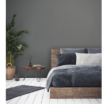 Schlafzimmer mit Holzbett, Nachttisch und Zimmerpflanze