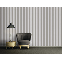 Wohnzimmer mit gestreifter Tapete, Sessel, Lampe und Beistelltisch