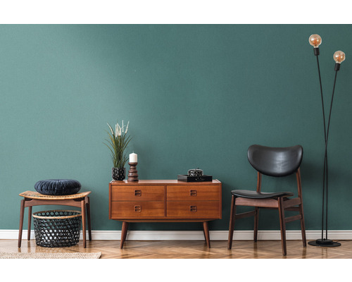 Wohnzimmer-Interieur mit Holzkommode, Stuhl, Stehlampe und Dekoration auf Parkettboden vor farbiger Wand