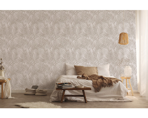 Schlafzimmer mit Bett vor einer Wand mit Blättermuster-Tapete.