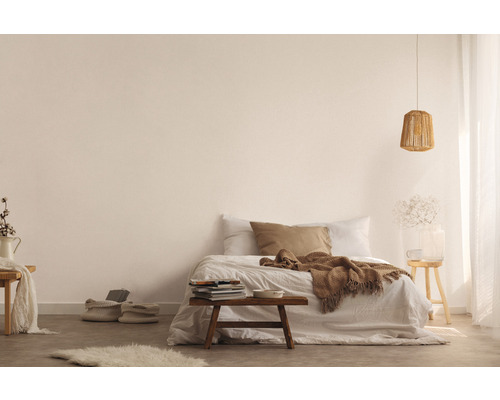 Hell gestalteter Schlafbereich mit Bett, Holzhocker, Lampe und dekorativen Elementen für eine freundliche Atmosphäre