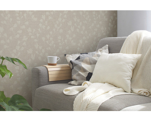 Wohnzimmer mit floral gemusterter Tapete, Sofa, Kissen und Getränkehalter