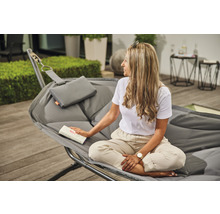 Frau liest in einer grauen Hängematte mit Kissen auf einer Terrasse