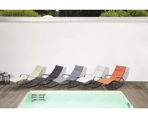 Mehrere Liegestühle unterschiedlicher Farben stehen neben einem Pool.