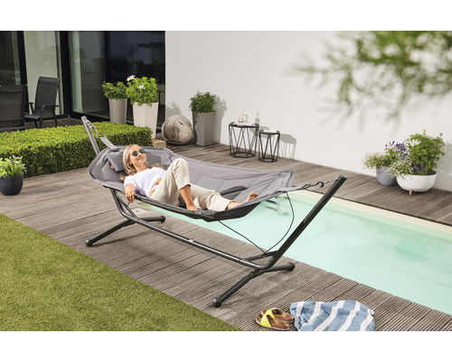 Frau entspannt sich in Hängematte mit Gestell auf Terrasse