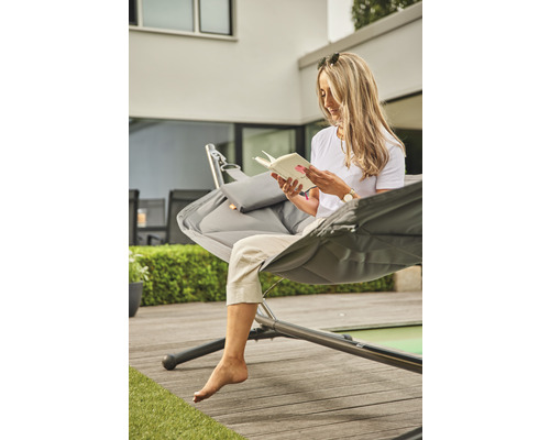 Frau liest Buch in Hängematte im Garten
