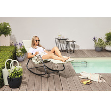 Szene mit Frau, die auf einer Schaukelliege am Pool entspannt, mit Beistelltischen und Pflanzenkübeln