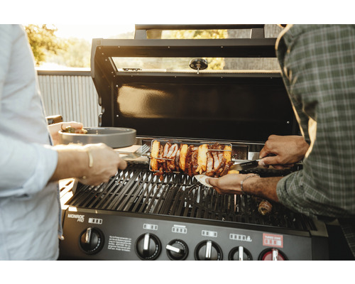 Gasgrill mit Drehspieß und Personen beim Grillen von Speisen.