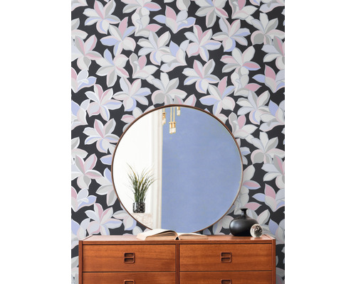Dekoratives Interieur mit einer Kommode vor einer floralen Tapete und einem runden Spiegel.
