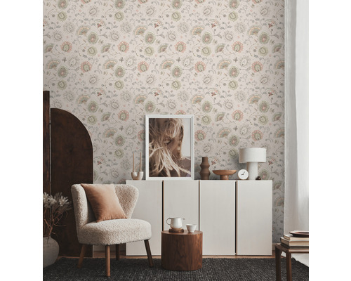Helles Wohnzimmer mit floral gemusterter Tapete, Sessel und Kommode