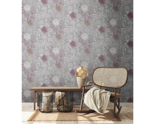 Dekoratives Interieur mit einer floral gemusterten Tapete, einem Holzbänkchen und einem Schaukelstuhl.