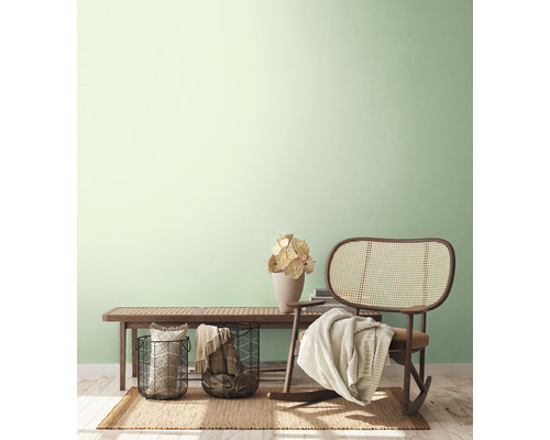 Helle, freundliche Inneneinrichtung mit Sitzbank, Rattansessel, Körben und Dekoration auf einem Teppich.