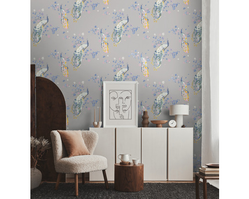 Helles Zimmer mit Tapete mit Pfauenmuster, Sessel, Sideboard und Dekorationen für eine wohnliche Atmosphäre.