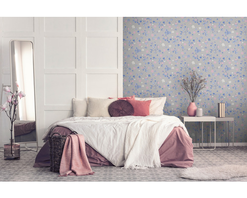 Schlafzimmer mit Bett, Spiegel und blumiger Tapete für eine gemütliche Atmosphäre.