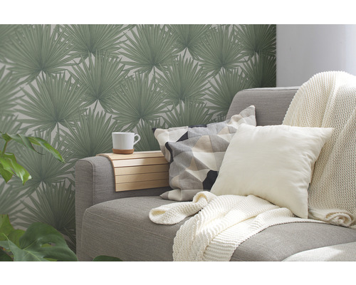 Wohnzimmer mit grauer Couch, Kissen, Decke und gemusterter Tapete mit Palmenmotiven