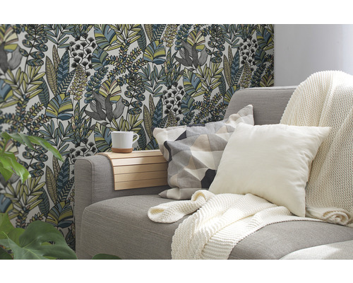 Wohnzimmer mit Sofa, Kissen, Decke und floraler Tapete