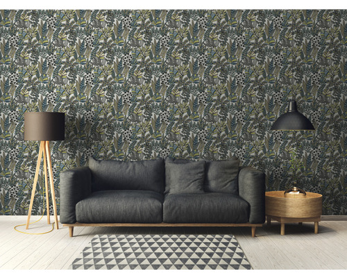 Wohnzimmer mit gemusterter Blättertapete, Sofa, Stehlampe, Teppich und Beistelltisch.