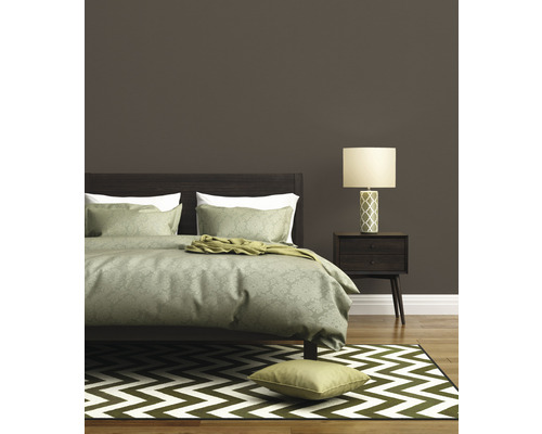 Schlafzimmer mit Bett, Nachttischlampe und Teppich im Zickzackmuster