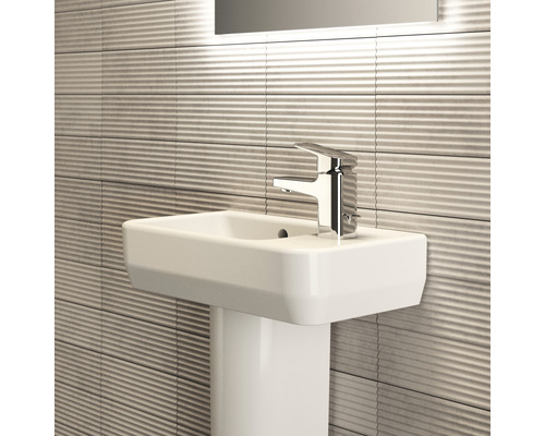 Waschtisch mit Armatur und geriffelten Fliesen im Badezimmer