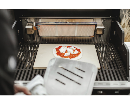 Grill mit Pizzastein und Pizza mit Tomatensoße und Käse
