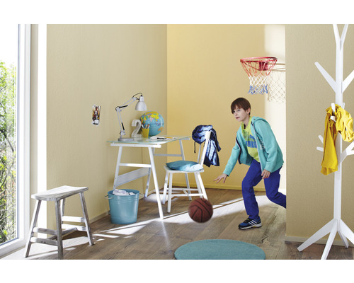 Helles Kinderzimmer mit Schreibtisch, Stuhl, Basketballkorb und spielendem Kind