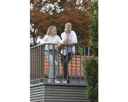 Ein junges Paar steht auf einem Balkon mit Metallgeländer.