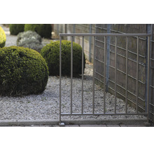 Metallzaun im Garten mit Kies und Sträuchern