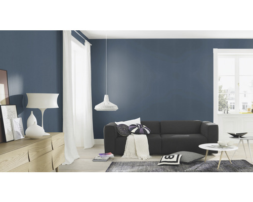 Wohnzimmer mit Couch, Kommode, Lampe und Dekoration vor dunkelblauer Wand