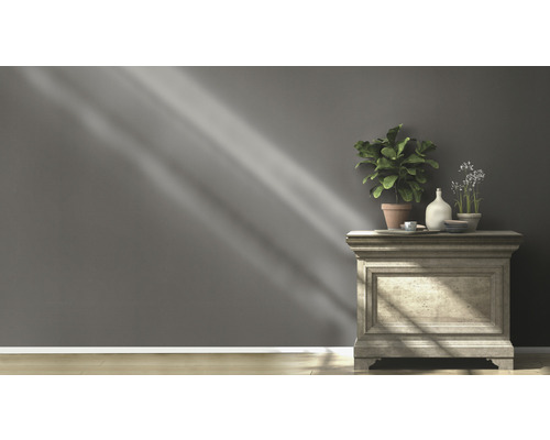 Dekorative Kommode mit Pflanzen und Dekoartikeln vor einer grauen Wand