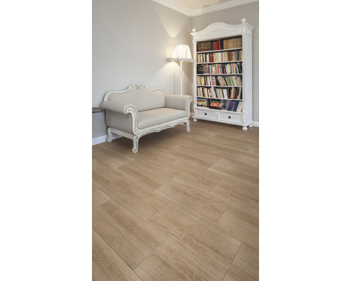 Heller Raum mit Bücherregal, Sofa und Bodenfliesen in Holzoptik.