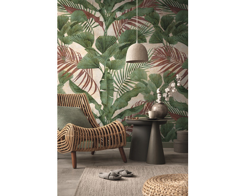 Wohnzimmer mit Rattansessel, Beistelltisch und botanischer Tapete mit Blättern