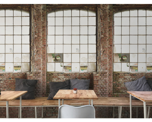 Innenraum mit Ziegelwand und großen Fenstern sowie Tischen und Sitzgelegenheiten.