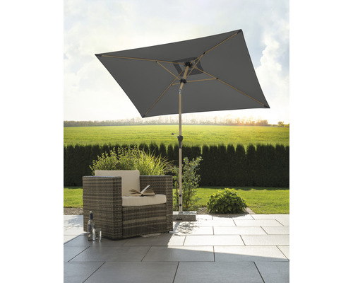 Quadratischer Gartenschirm neben Korbsessel auf Terrasse