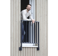 Mann lehnt an einem Fenstergitter an einem Gebäude mit Holzfassade.