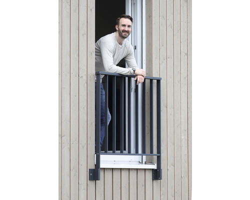 Mann lehnt sich an einen Fenstergitterbalkon